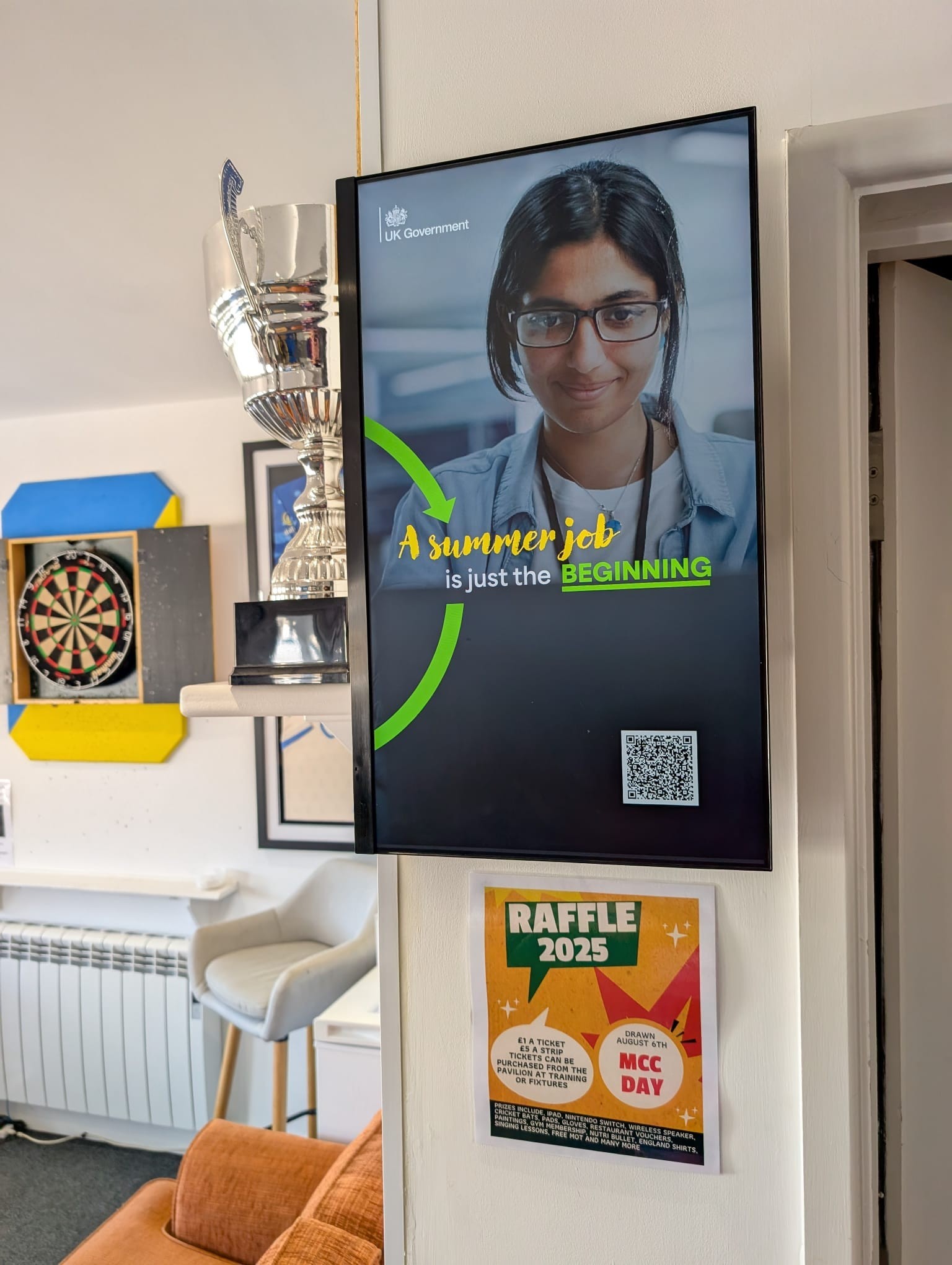 UK Government summer careers campaign on a portrait Grassroot Media screen inside a cricket clubhouse.