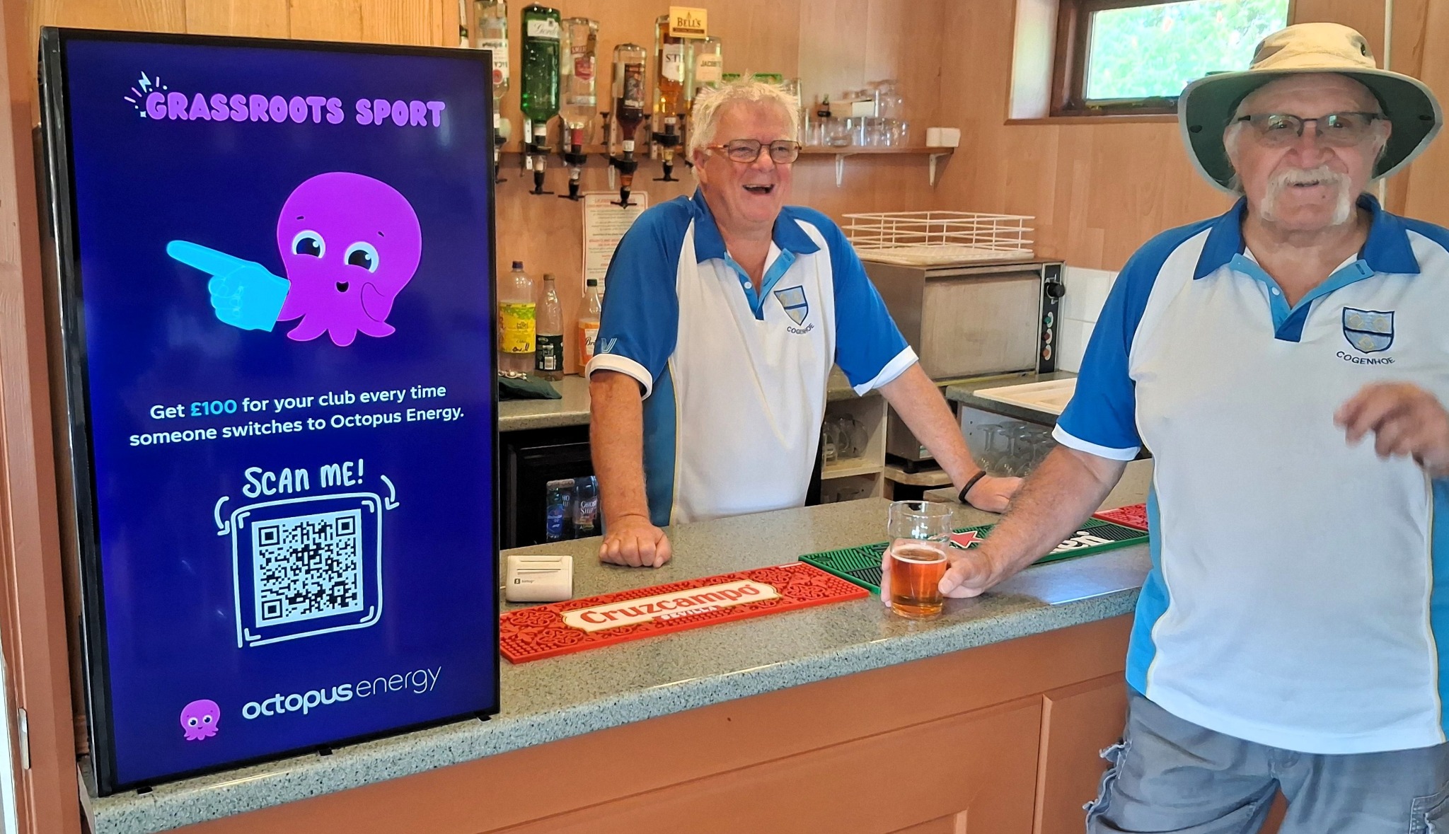 Octopus Energy campaign on a portrait Grassroot Media screen beside bowls club members at the bar.