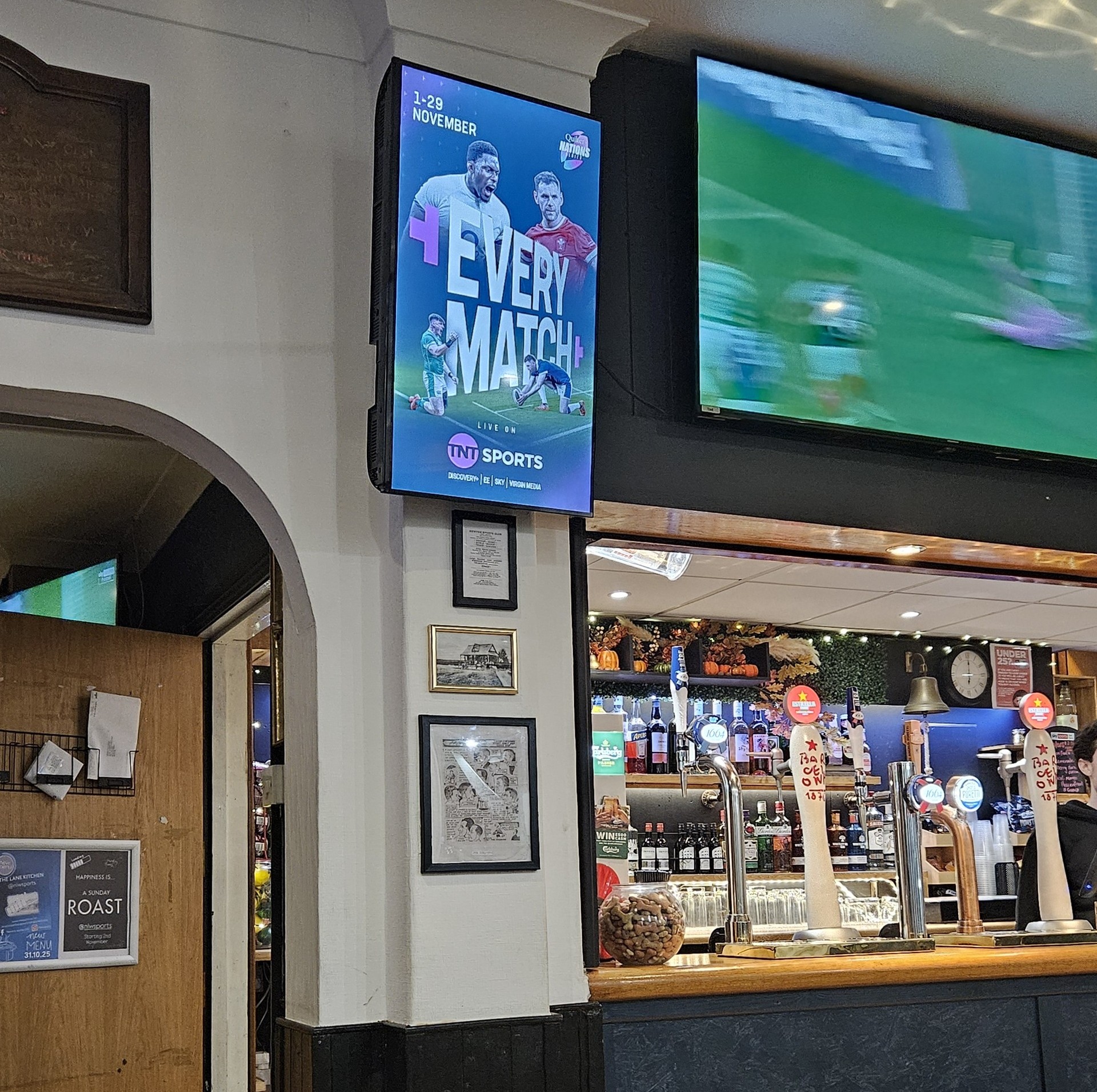 TNT Sports campaign on a portrait Grassroot Media screen beside live sport in a rugby clubhouse bar.