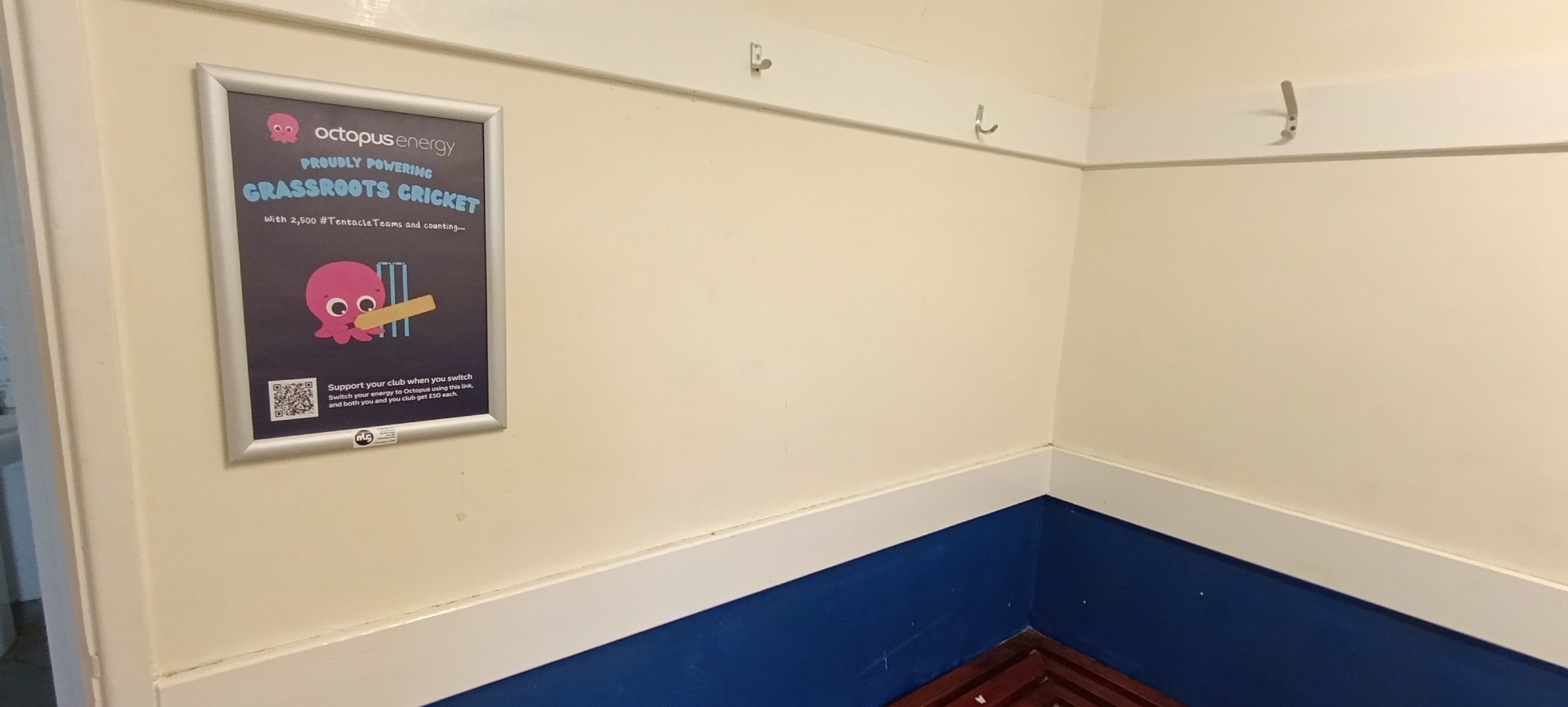 Octopus Energy grassroots cricket campaign poster displayed inside a cricket club changing room.