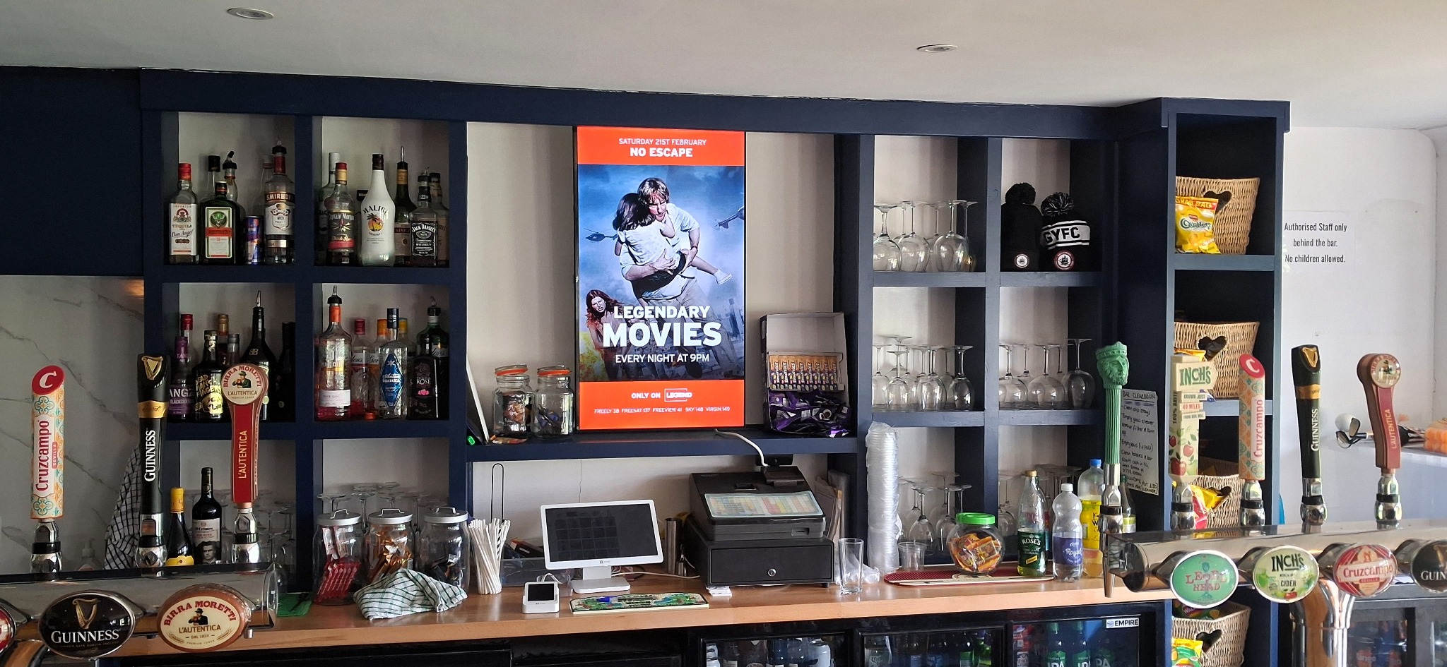 Grassroot Media screen showing an AMC campaign above a real club bar.