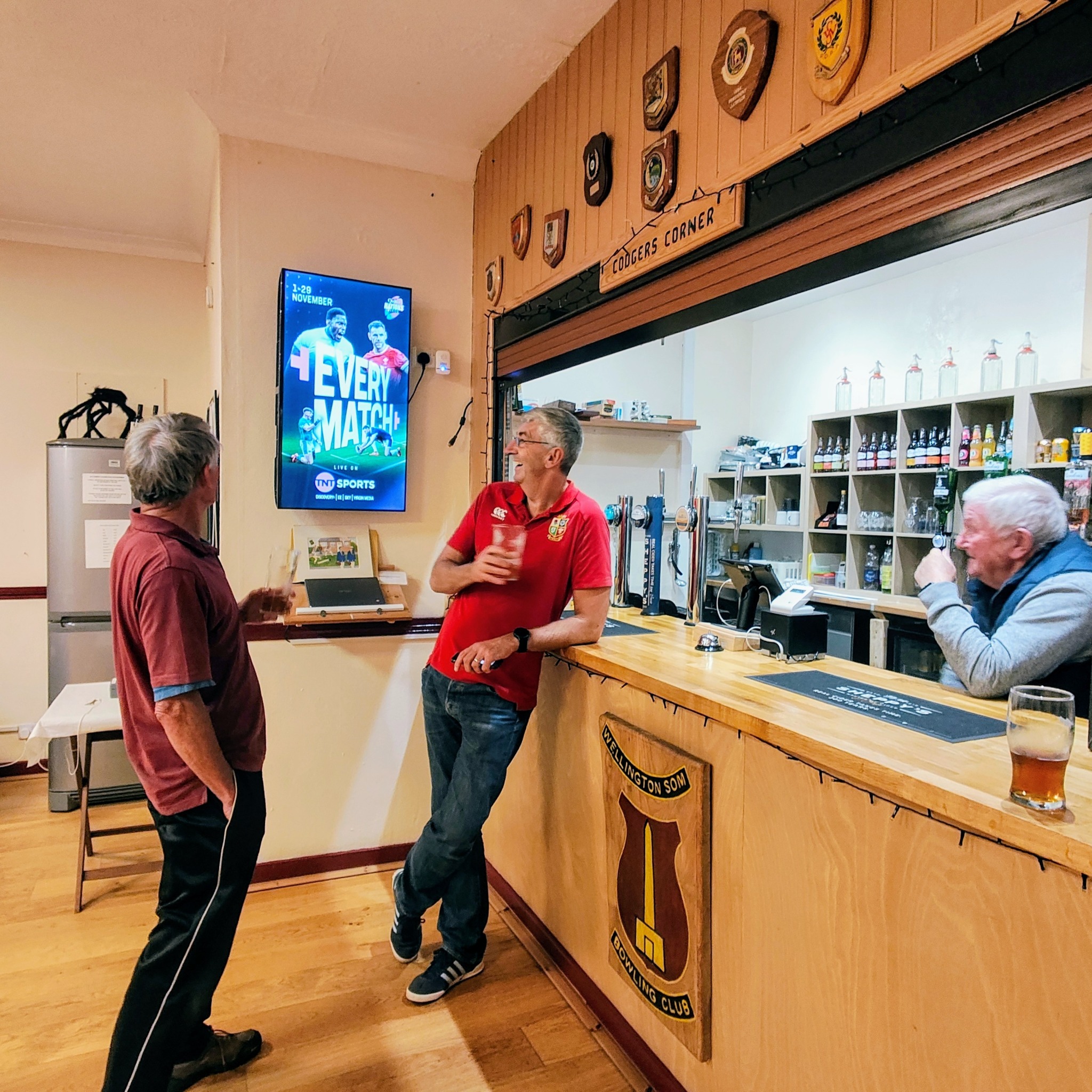 Club members looking at a TNT Sports digital advertising screen inside Wellington Som Bowling Club.
