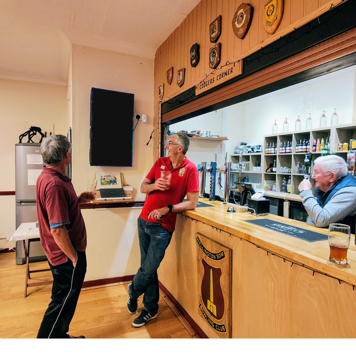Rugby clubhouse bar showing people and the real environment around a portrait digital screen.