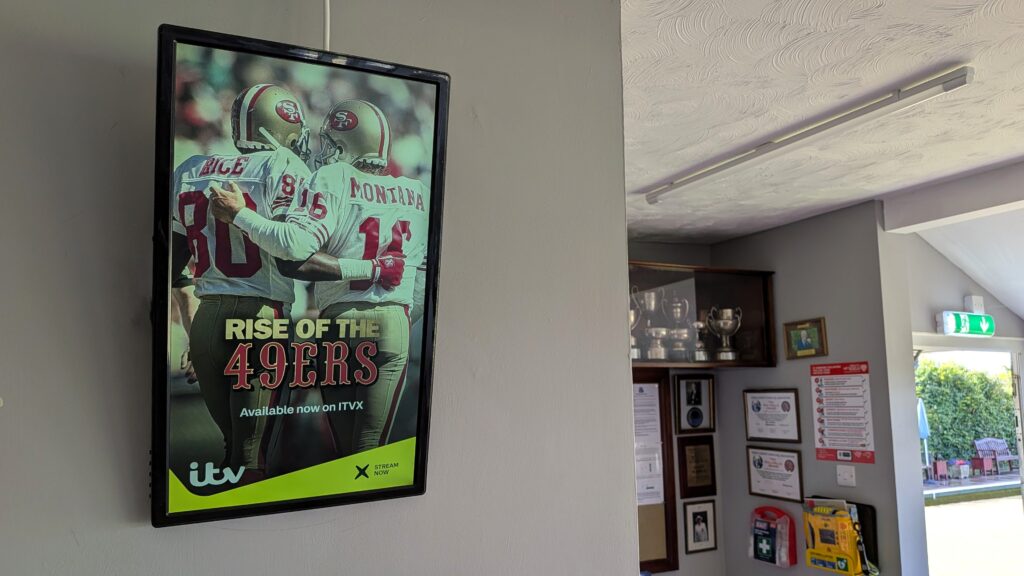 ITVX Rise of the 49ers advert displayed on a portrait digital screen inside a bowls clubhouse.