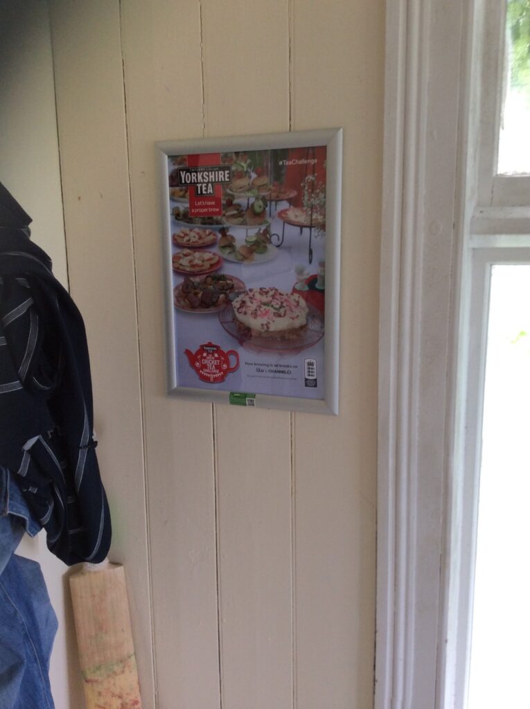 Framed Yorkshire Tea advertising poster displayed on a panelled wall inside a cricket club.