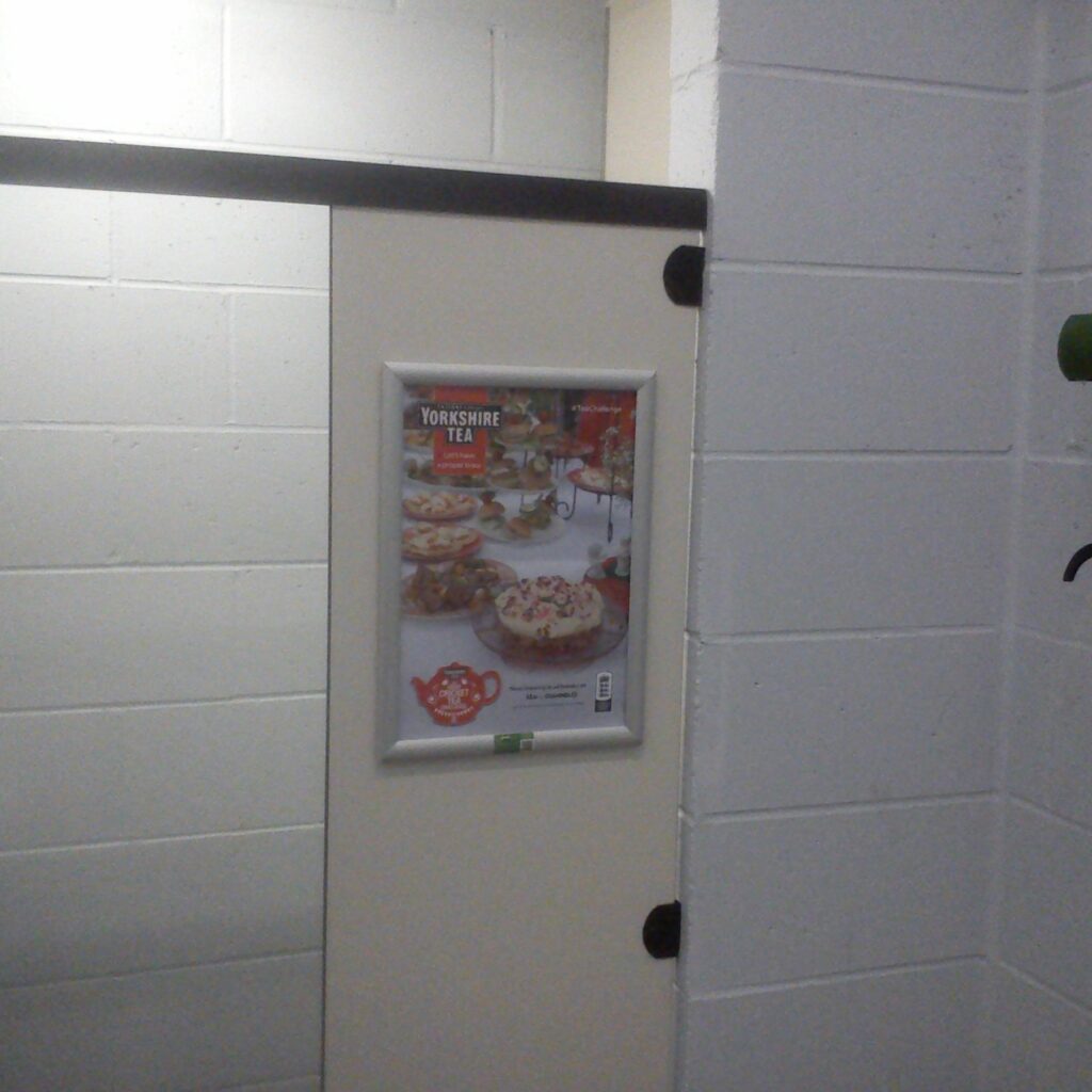 Framed Yorkshire Tea advertising poster displayed on a door inside Woodmansterne Cricket Club.