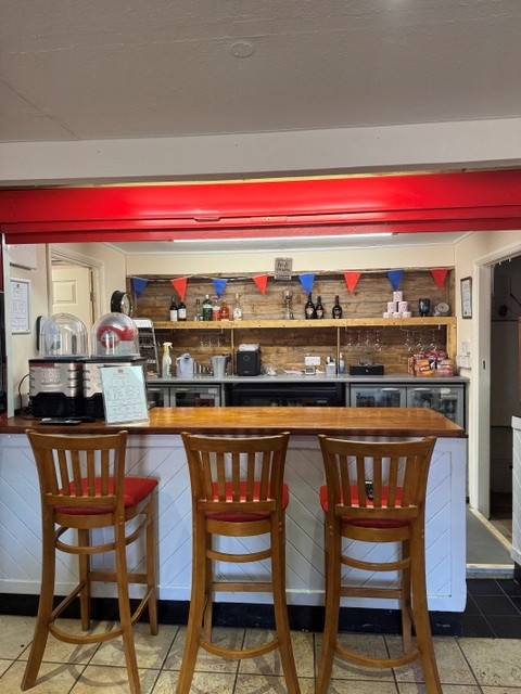 Bosham Football Club clubhouse bar with three stools and red and blue bunting