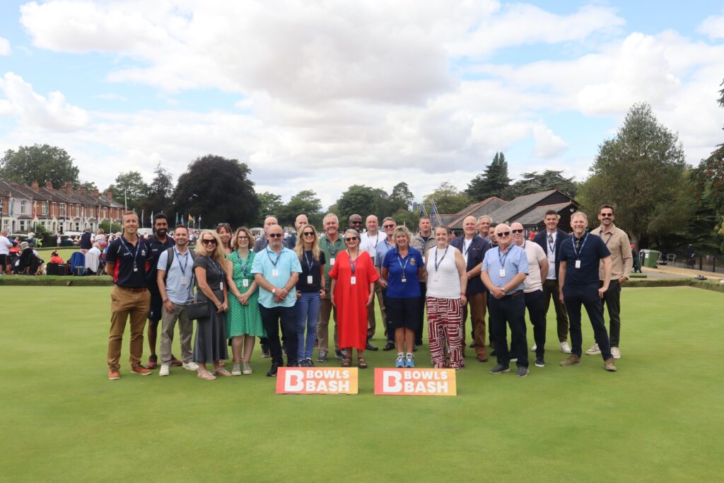 A group of hospitality guests standing together on the green at the National Bowls Finals