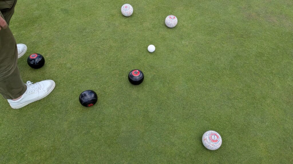 Several bowls positioned around the jack on a bowling green