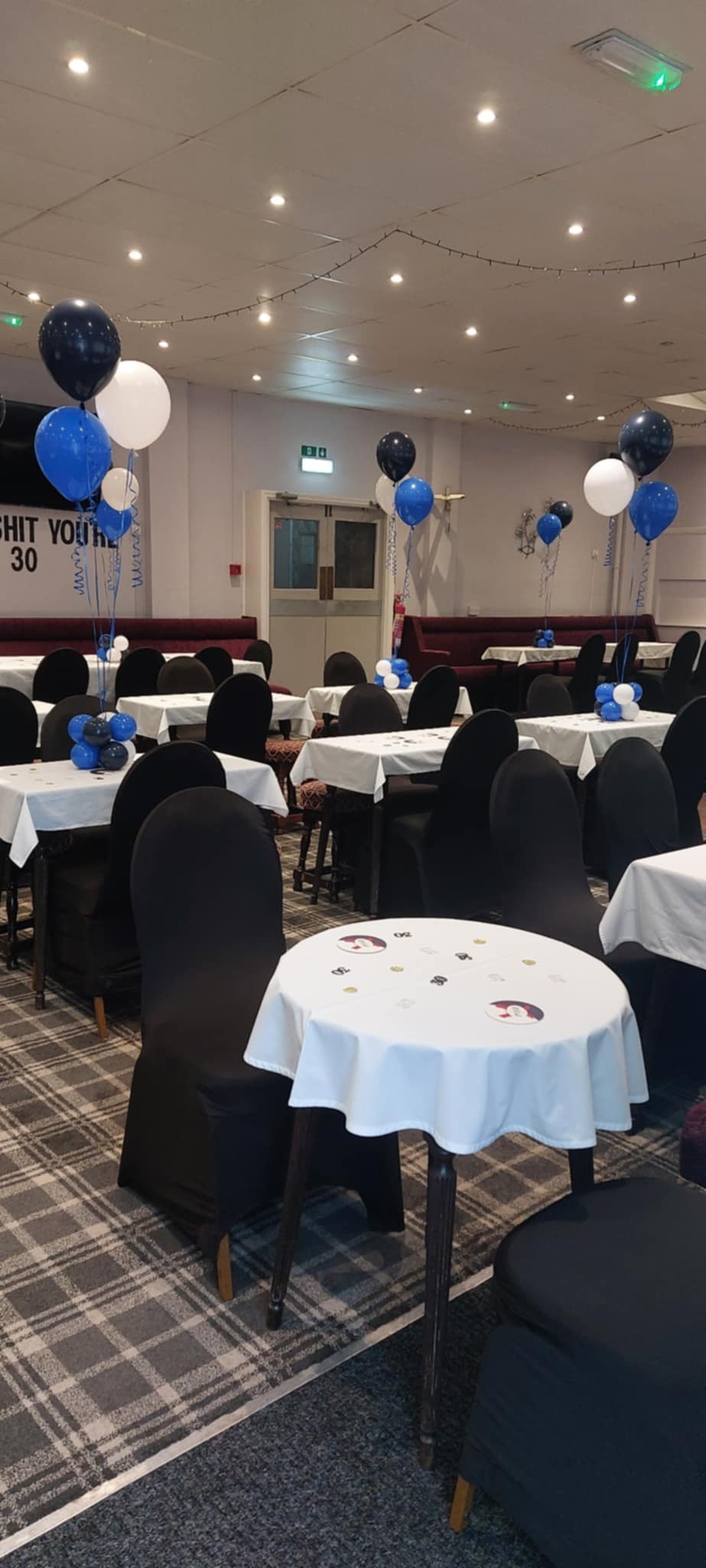 Frenchwood Social Club function room set with tables, black chair covers and blue, black and white balloons