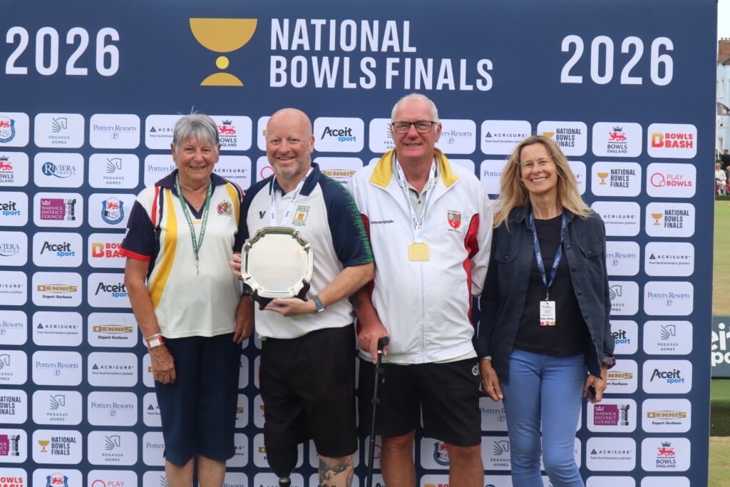 Bowls players and a guest photographed in front of the National Bowls Finals 2026 media wall